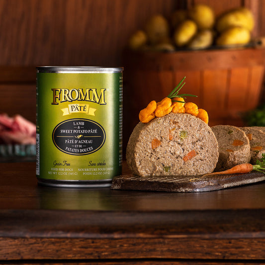 Fromm Lamb & Sweet Potato Pâté can beside slices of pâté topped with orange vegetables on a wooden board