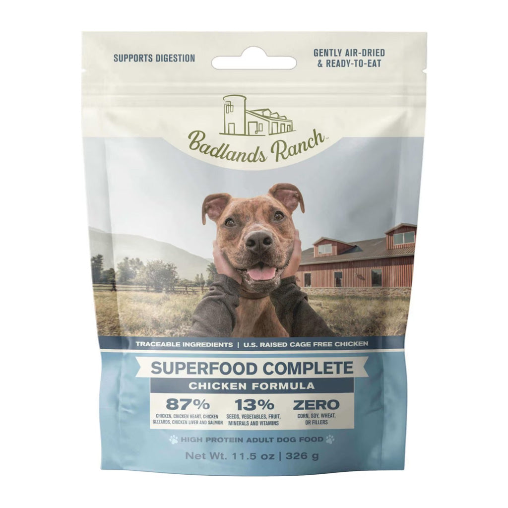 Front of Badlands Ranch Superfood Complete Chicken Formula air-dried dog food pouch, with a blue label and a brown dog at a ranch.