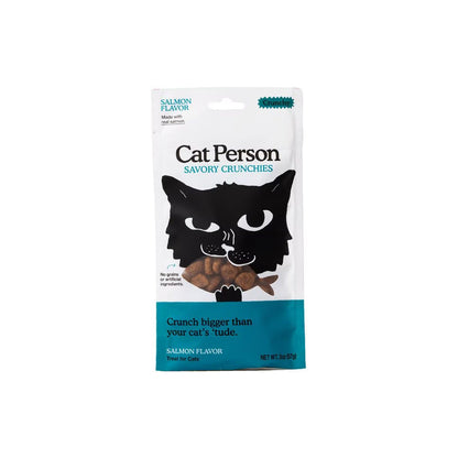 Front of a white and teal 2 oz Cat Person Salmon Flavor Savory Crunchies cat treat bag, with a black cat illustration and fish-shaped treats.