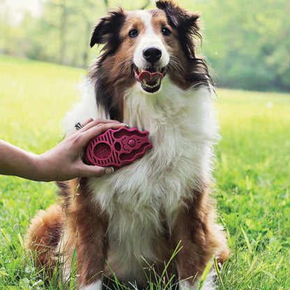 Person grooming a long-haired dog’s chest with a pink KONG ZoomGroom brush outdoors.