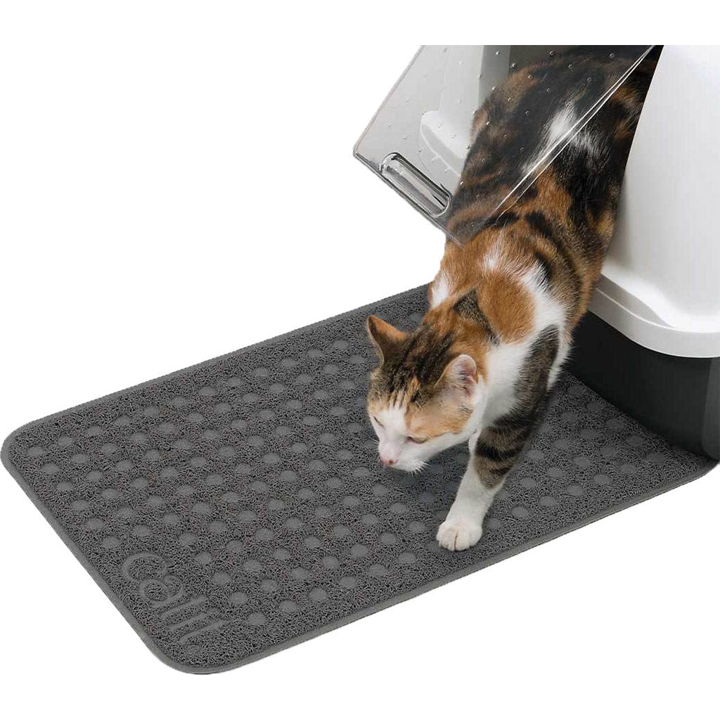 Calico cat stepping out of a covered litter box onto a gray Catit litter mat with a textured litter-trapping surface.