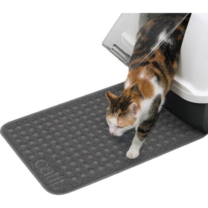 Calico cat stepping out of a covered litter box onto a gray Catit litter mat with a textured litter-trapping surface.