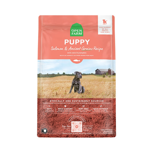 Front of coral Open Farm Puppy Salmon and Ancient Grains Recipe dry dog food bag with a puppy pictured in a field