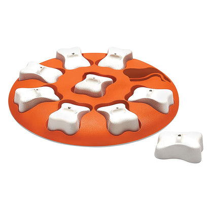 Orange circular Dog Smart treat puzzle with removable white bone-shaped covers over the recessed treat compartments.
