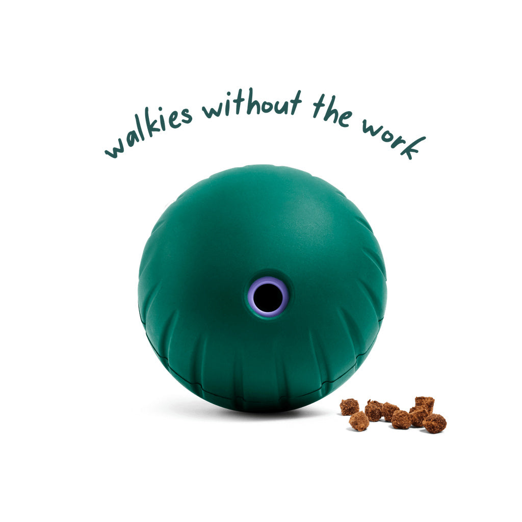 Green Woof Walkabout rolling slow feeder with a purple food opening and kibble beside it, under the words “walkies without the work.”